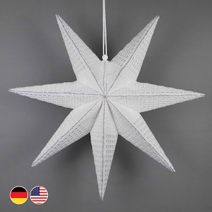 May include: A large, white, eight-pointed star decoration with a textured surface and silver trim. The star is suspended by a white string, perfect for hanging. Ideal for holiday decor, this star adds a festive touch to any space.