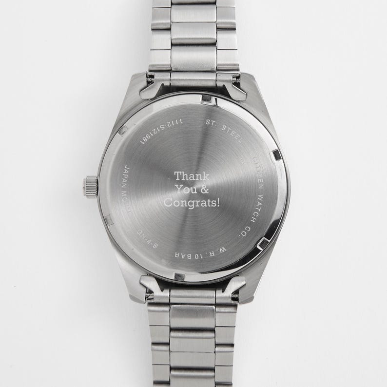 Puede incluir: Un reloj de acero inoxidable con una correa plateada. La esfera del reloj tiene el texto "Thank You & Congrats!". El reloj es de Citizen Watch Co. y es resistente al agua hasta 10 bar.
