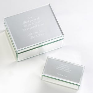 May include: Two mirrored jewelry boxes with personalized messages. The larger box has a message for "Mom" and the smaller box has a message for "Grandma".