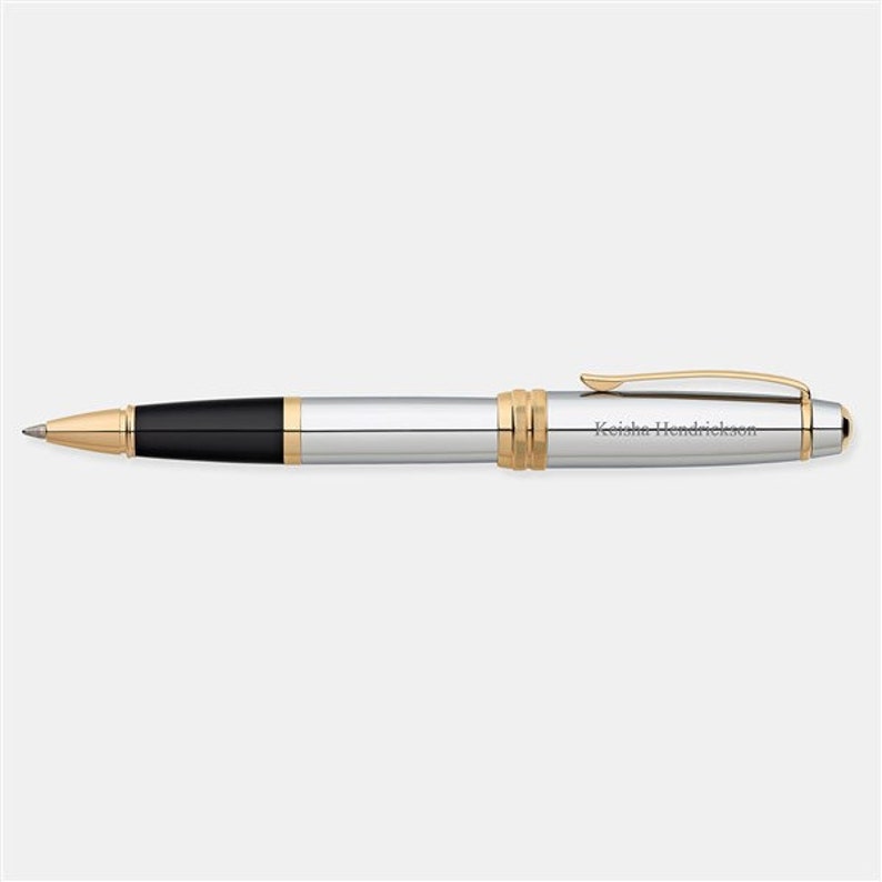 May include: A silver and gold pen with a black ink cartridge. The pen is engraved with the name "Keisha Hendrickson".