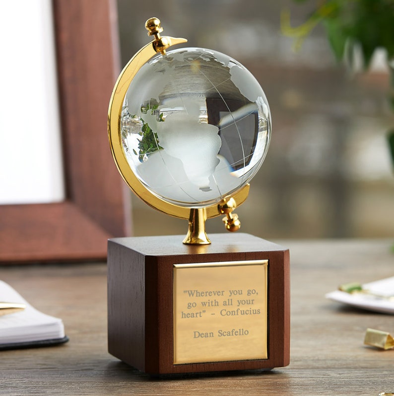 May include: A small, clear glass globe on a wooden base with a gold metal stand. The globe has a frosted map of the world. The base has a gold plaque with the quote "Wherever you go, go with all your heart" - Confucius and the name Dean Scafello.