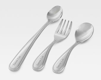 May include: A set of three silver baby utensils with beaded handles. The spoon and fork are engraved with the name "Tatem Liu".