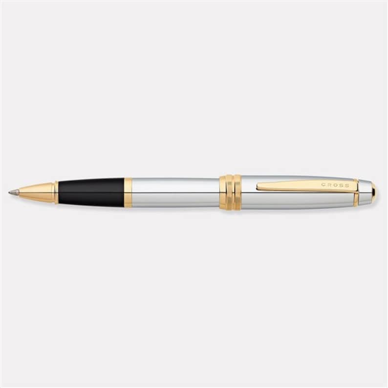 May include: A silver and gold Cross pen with a black ink cartridge. The pen has a gold band around the barrel and a gold clip.