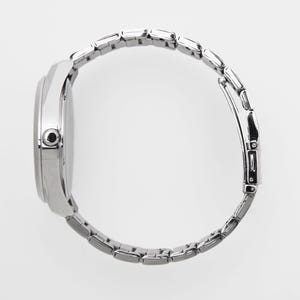 Puede incluir: Vista lateral de un reloj de pulsera plateado con una correa de metal con eslabones. La esfera del reloj es redonda y la correa est&aacute; compuesta por peque&ntilde;os eslabones rectangulares. El reloj est&aacute; sobre un fondo blanco.