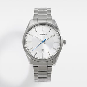 Puede incluir: Un reloj Citizen plateado con esfera blanca, agujas azules y visualizaci&oacute;n de fecha a las 3. El reloj tiene una correa de acero inoxidable y un bisel redondo. El reloj tiene un dise&ntilde;o cl&aacute;sico.