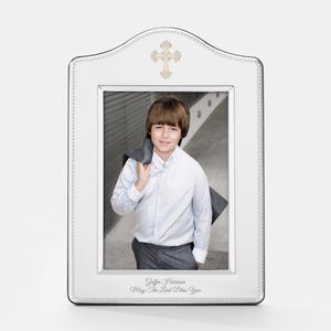 May include: Silver-plated picture frame with a beaded border and a cross design. The frame has a white mat and a photo of a young boy. The inscription reads "Griffin Harrison May The Lord Bless You".