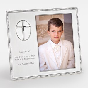 May include: Silver picture frame with a cross design and a photo of a young boy in a white suit. The frame has a personalized inscription that reads "Issac Kendall God Bless You on Your First Holy Communion. Love, Grandma Mae."