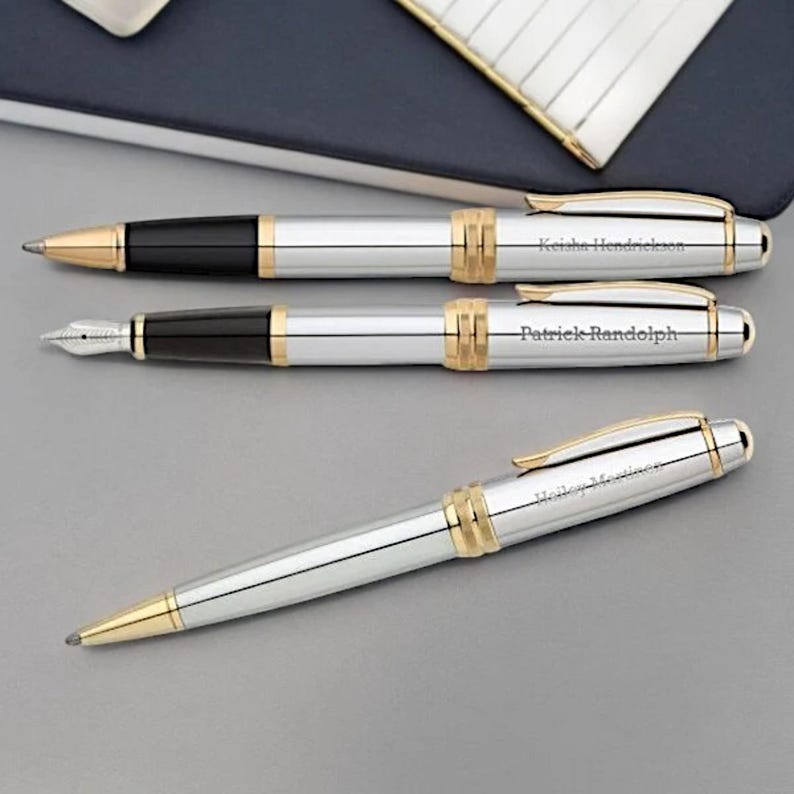 May include: Three silver and gold pens with black ink cartridges. The pens are engraved with the names "Keisha Hendrickson", "Patrick Randolph", and "Hollie Martinez".