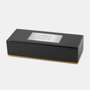May include: A black rectangular box with a gold trim. The box has a silver plaque with the text "Congratulations on your achievements and a fantastic year!"