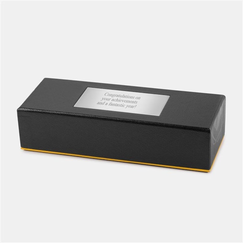 May include: A black rectangular box with a gold trim. The box has a silver plaque with the text "Congratulations on your achievements and a fantastic year!"
