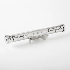 May include: Silver metal scroll with the word "Marriage" engraved on it. The scroll is on a stand and has a small oval plaque with the text "Julietta & Colby Nesbit, Forever Begins May 12, 2018" engraved on it. The scroll also has the word "Certificate" engraved on it.