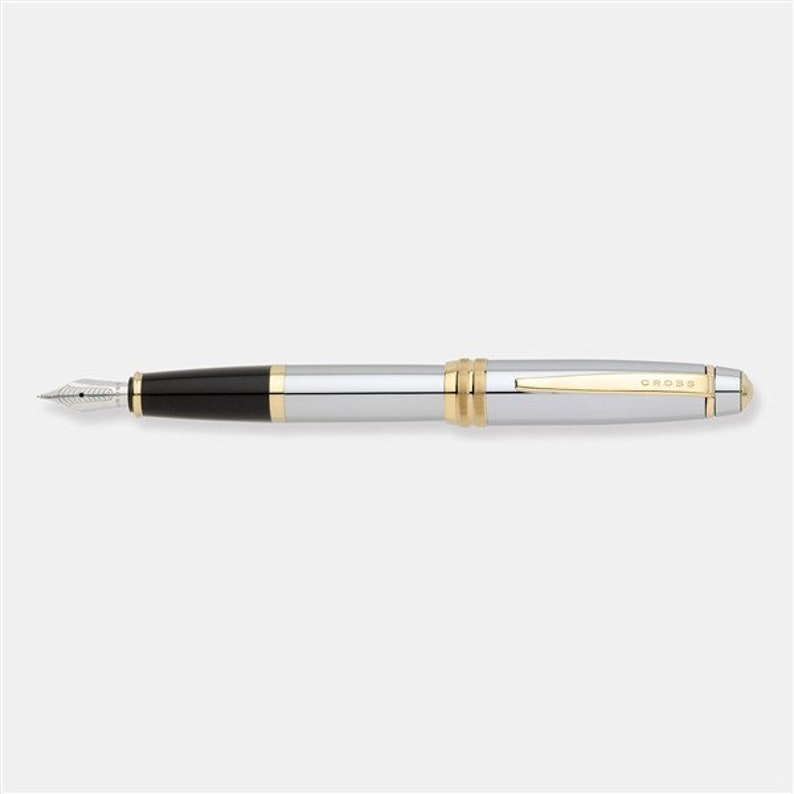 May include: A silver and gold Cross fountain pen with a black ink cartridge.