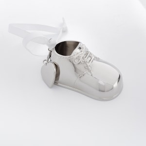 May include: Silver baby shoe ornament with a heart charm. The shoe has a lace-up design and a shiny finish.