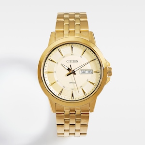 May include: A gold-toned Citizen wristwatch with a cream-colored face. The watch features gold hands and markers, a date display, and a gold link band. The watch face displays the text "Citizen" and "WR 50".