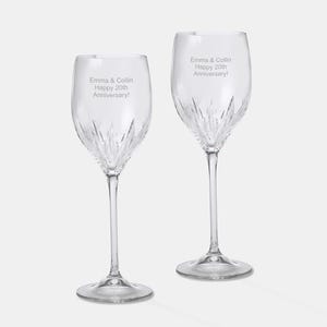 May include: Two clear glass wine glasses with a diamond-cut pattern. The glasses are engraved with the text "Emma & Collin Happy 20th Anniversary!"