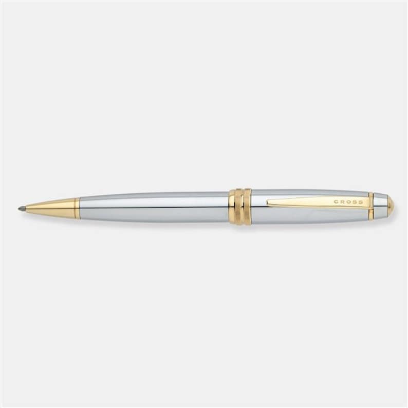 May include: A silver and gold Cross pen with a classic design. The pen has a gold band near the tip and the word "CROSS" is engraved on the barrel.