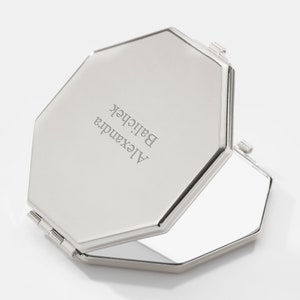 May include: A silver octagonal compact mirror with a hinged lid. The lid is engraved with the text "Alexandra Balichek".