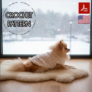 Puede incluir: Un perro pequeño, de color marrón claro, con un suéter de ganchillo blanco, tumbado sobre una alfombra color crema. La imagen incluye el texto "CROCHET PATTERN" en un diseño circular, un icono PDF y la bandera estadounidense.