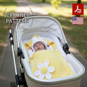 Puede incluir: Un bebé en un cochecito está envuelto en una manta amarilla de ganchillo con una gran aplicación de margarita blanca. El bebé lleva un gorro blanco con un lazo. La imagen incluye el texto "CROCHET PATTERN".