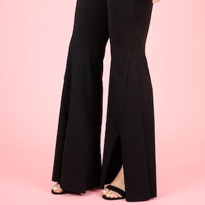 May include: Black high-waisted wide-leg pants with a slit on each side. The pants are made of a stretchy fabric and have a fitted silhouette.