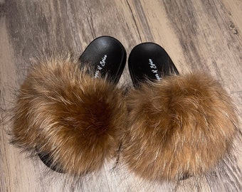 May include: A pair of black faux fur slides with brown fur. The slides have the text "Sugar N Spice" on the straps.