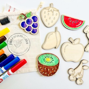 K&ouml;nnte beinhalten: Ein Set aus acht Holzfr&uuml;chten, darunter eine Erdbeere, eine Wassermelone, eine Mango, ein Apfel, eine Kiwi, Trauben, eine Banane und Kirschen. Die Formen sind unbemalt und bereit, mit Markern bemalt zu werden. Das Set enth&auml;lt auch eine T&uuml;te mit Markern.