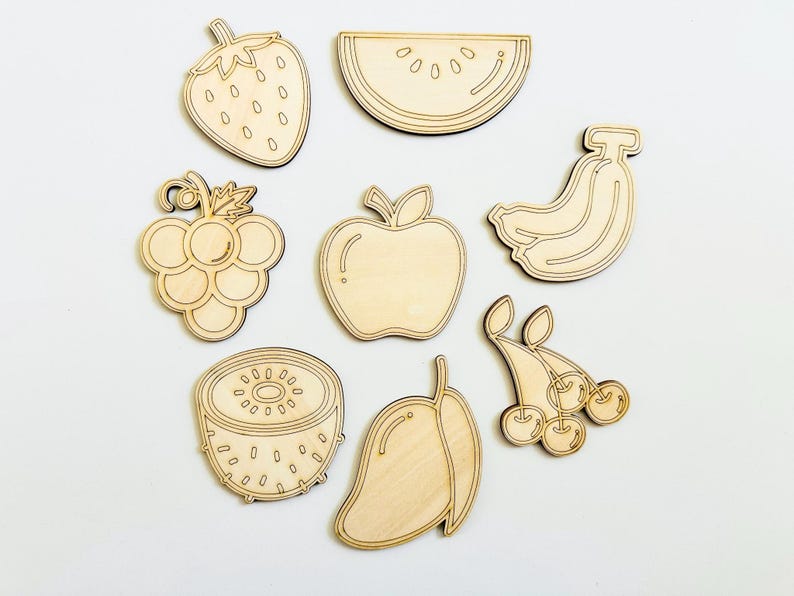 K&ouml;nnte beinhalten: Satz von acht unfertigen Holzfr&uuml;chten, darunter eine Erdbeere, Trauben, ein Apfel, eine Wassermelone, eine Banane, eine Kiwi, eine Mango und Kirschen. Die Formen sind bereit zum Bemalen oder Dekorieren.