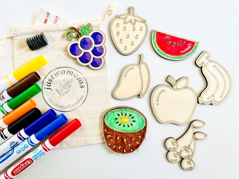 K&ouml;nnte beinhalten: Ein Set aus acht Holzfr&uuml;chten, darunter eine Erdbeere, eine Wassermelone, eine Mango, ein Apfel, eine Kiwi, Trauben, eine Banane und Kirschen. Die Formen sind unbemalt und bereit, mit Markern bemalt zu werden. Das Set enth&auml;lt auch eine T&uuml;te mit Markern.