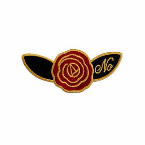 May include: An embroidered patch featuring a central red rose with gold stitching, flanked by two black leaf-shaped wings outlined in gold. The right wing displays the word No in elegant gold cursive script, creating a distinct decorative emblem.