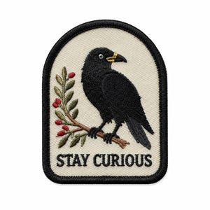 May include: An embroidered patch with a cream-colored background and a black border. It features a black crow perched on a brown branch with green leaves and red berries. The text STAY CURIOUS is embroidered in black capital letters at the bottom.