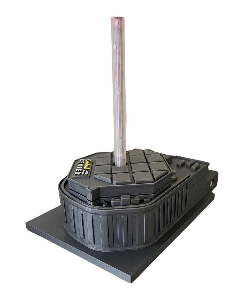 May include: A black plastic base with a round, textured top. The base has a label that reads "Golden Leaf Center". A clear plastic tube is inserted into the top of the base.