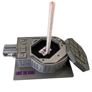 May include: A gray model of the Golden 1 Center, home of the Sacramento Kings, with a clear plastic beam extending from the top. The model has a removable roof and the words "Light the Beam" are printed on the base.