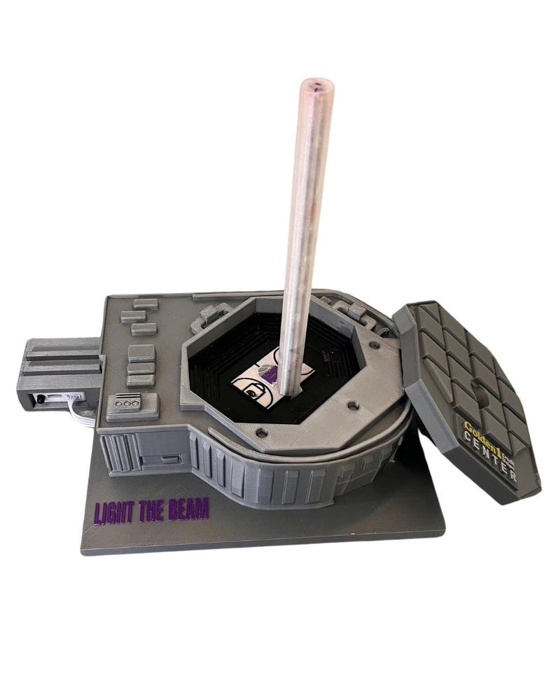 May include: A gray model of the Golden 1 Center, home of the Sacramento Kings, with a clear plastic beam extending from the top. The model has a removable roof and the words "Light the Beam" are printed on the base.