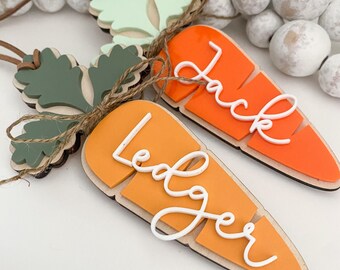 May include: Two wooden carrot ornaments with green tops and white lettering. The top carrot says "Jack" and the bottom carrot says "Ledger".