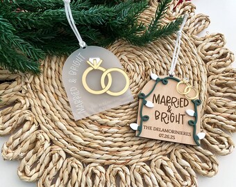 May include: Two wedding-themed ornaments. One is clear with gold rings and the text "Married & Bright." The other is wooden with gold rings, the text "Married & Bright," and the names and date "07.26.25."
