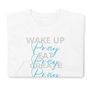 May include: White t-shirt with the text "WAKE UP Pray EAT Pray CREATE Pray" in blue and gray lettering.