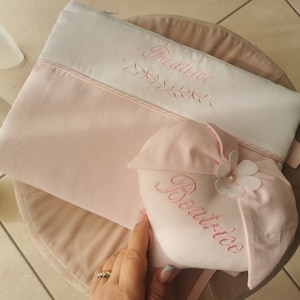 May include: A pink and white zippered pouch with the name "Beatrice" embroidered on it. A pink and white heart-shaped pillow with the name "Beatrice" embroidered on it is next to the pouch.