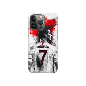 May include: A white phone case with a graphic of a soccer player in a white jersey. The jersey displays the name "RONALDO" and the number "7" in red. A red splash design is in the background, adding a dynamic element.