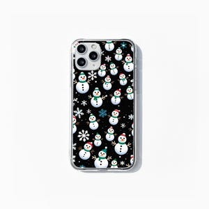 May include: A clear phone case with a black background and a repeating pattern of white snowmen with green and red hats and blue snowflakes.