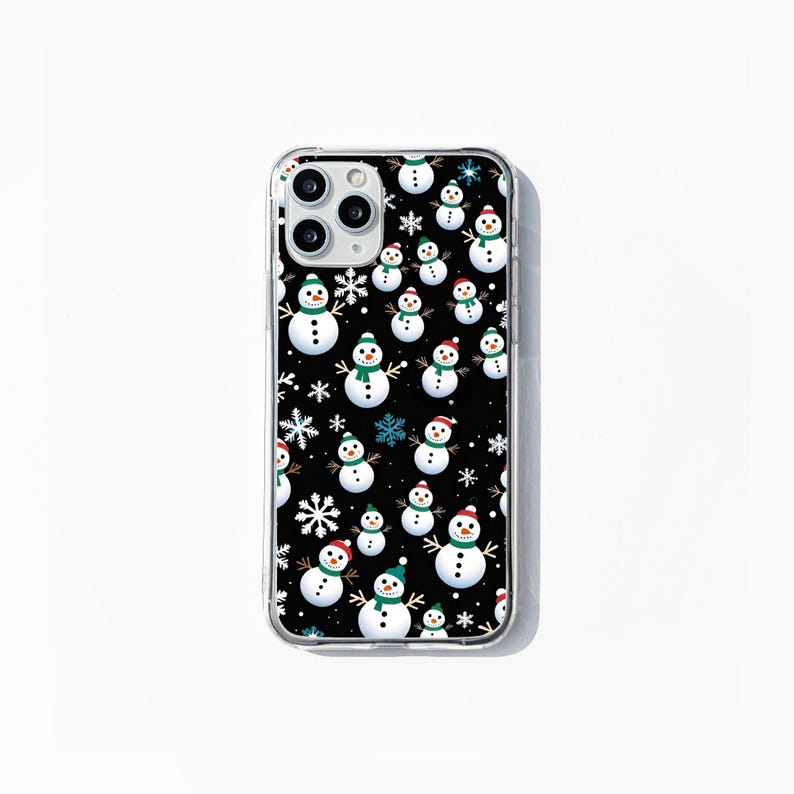 May include: A clear phone case with a black background and a repeating pattern of white snowmen with green and red hats and blue snowflakes.
