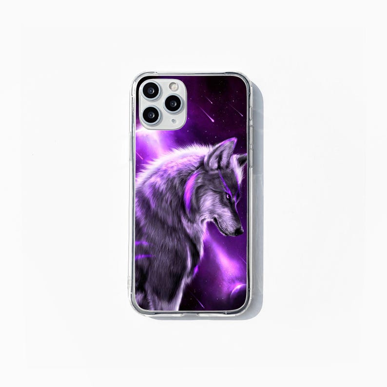 May include: Clear phone case with a detailed illustration of a wolf in shades of purple and grey. The background depicts a purple nebula with shooting stars. The phone case has a clear border and is designed for a smartphone.
