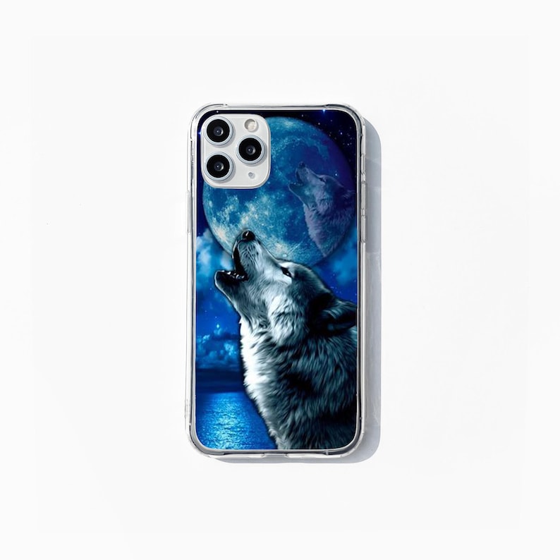 May include: Clear phone case with a detailed illustration of a grey wolf howling at a blue moon. The background shows a night sky with stars and water. The case has a clear border.
