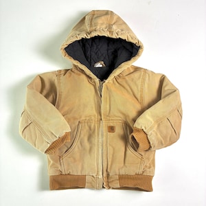 May include: A tan hooded jacket with a black quilted lining. The jacket features a full zipper, two front pockets, and ribbed cuffs and hem. A small logo patch is on the front pocket.