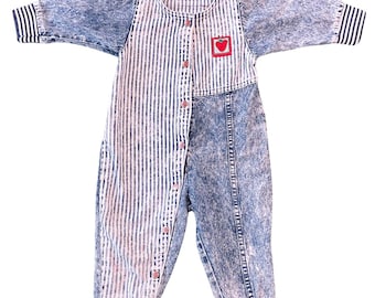 May include: A vintage baby jumpsuit with a unique design. The top half features vertical white stripes on a light background, while the sleeves and lower half are acid wash denim. A small red heart patch is on the chest. The jumpsuit has long sleeves and button closures.