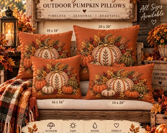 May include: Four square and rectangular orange throw pillows featuring a printed design of white pumpkins surrounded by autumn leaves. The pillows are labeled with sizes 18x18 inches, 20x20 inches, 16x16 inches, and 14x20 inches, displayed on a wooden bench.