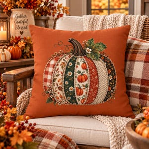 May include: A square throw pillow with a solid burnt orange background featuring a large central pumpkin graphic. The pumpkin is composed of vertical panels with various patterns including red plaid, floral prints, and green leaves.