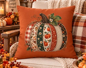 May include: A square throw pillow with a solid burnt orange background featuring a large central pumpkin graphic. The pumpkin is composed of vertical panels with various patterns including red plaid, floral prints, and green leaves.