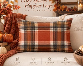 May include: A rectangular lumbar pillow featuring a plaid pattern in shades of burnt orange, brown, cream, and black. The pillow is labeled as 14 x 20 inches. The text "Cozy Spaces Happier Days FALL HOME DECOR" and "home feels better here" is visible.