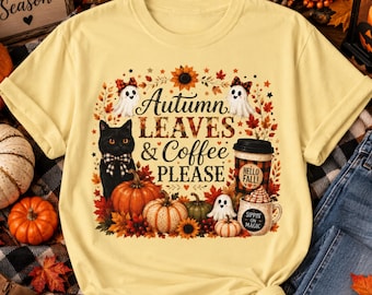 May include: A pale yellow t-shirt featuring a graphic print of a black cat with a plaid bow, pumpkins, ghosts, and a coffee cup. The text reads Autumn LEAVES & Coffee PLEASE, HELLO FALL, and SIPPIN ON MAGIC, surrounded by autumn leaves and sunflowers.