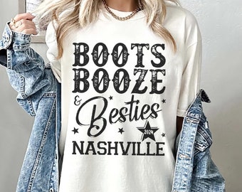 Può includere: T-shirt color avorio con la scritta "Boots Booze & Besties Nashville 2024" in un carattere nero invecchiato. La maglietta è abbinata a una giacca di jeans.